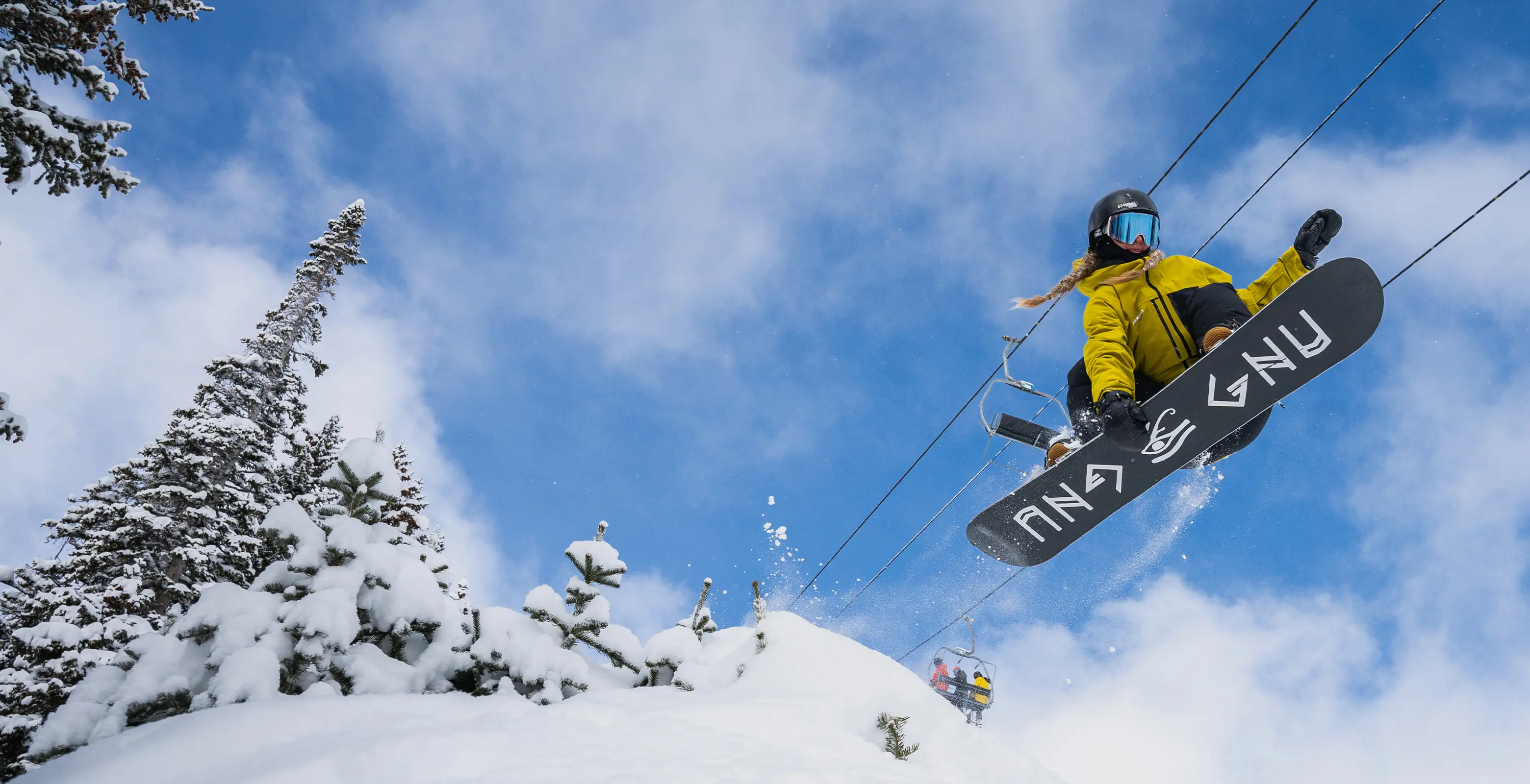 snowboarder hitting a jump on a bluebird day